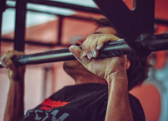 Focused shot of a man doing pull-ups in a gym, highlighting his strength and endurance.