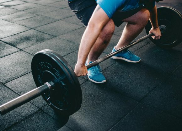 A man deadlifting a barbell indoors showcasing power, fitness, and dedication.